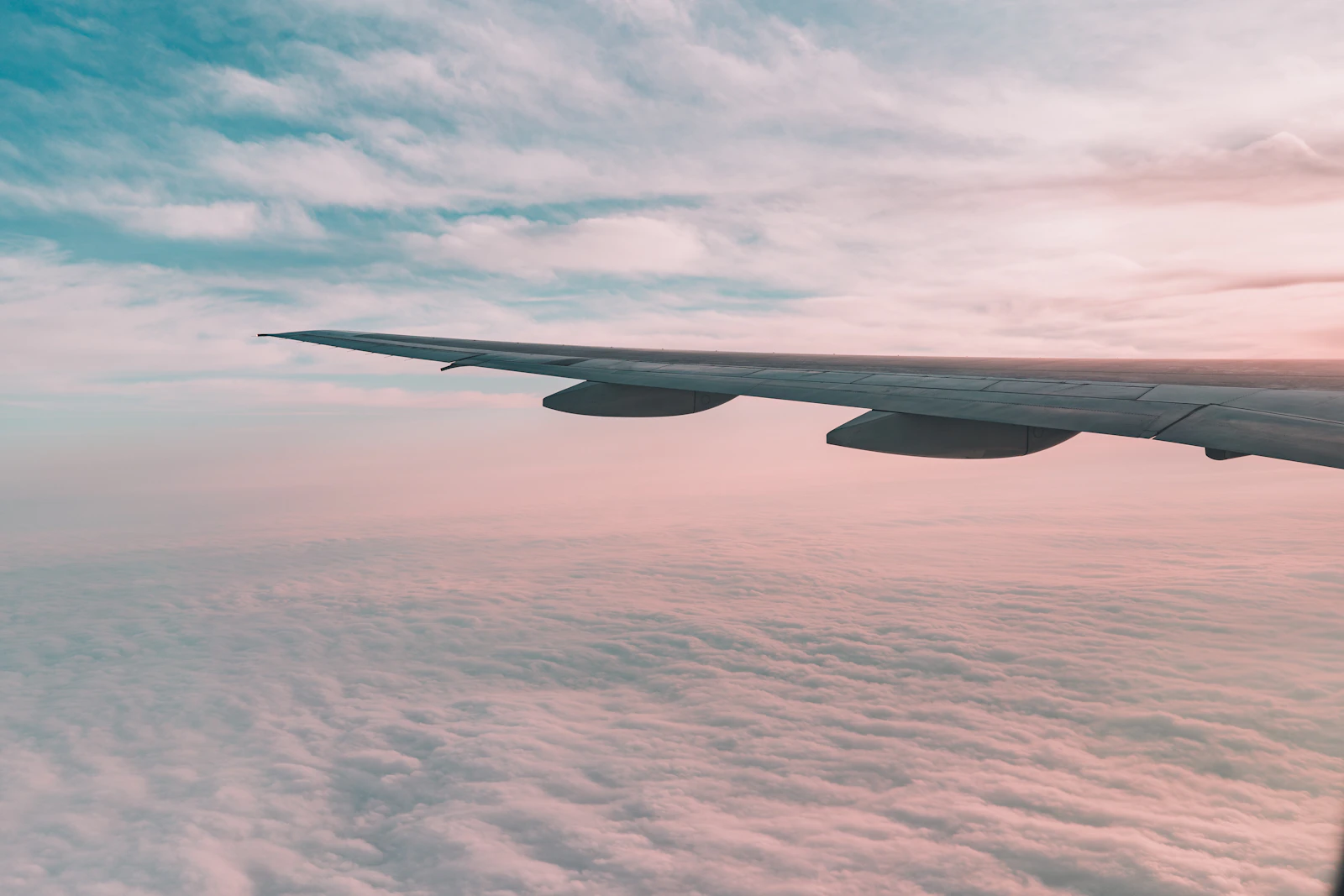 Asa de avião sobre mar de nuvens ao entardecer